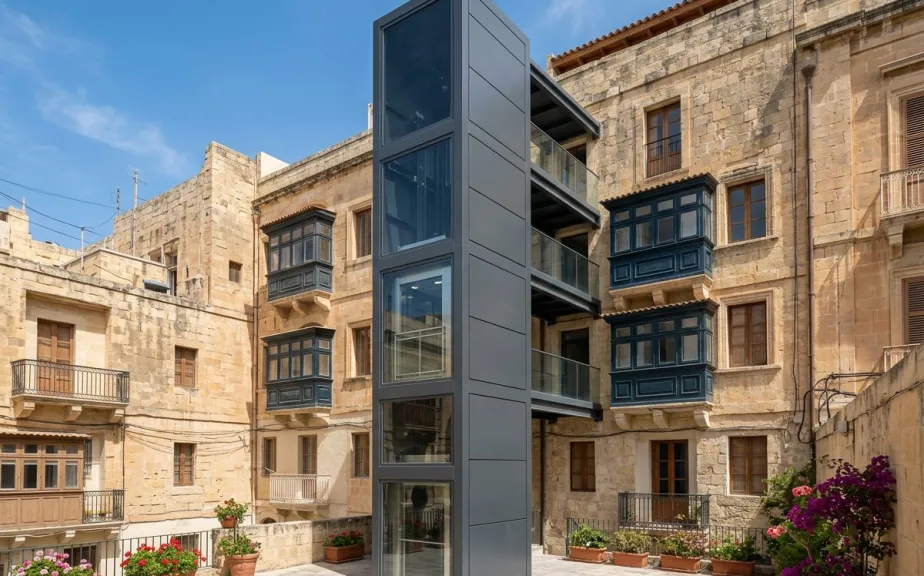 External lift tower with steel structure and glass panels on a Maltese building