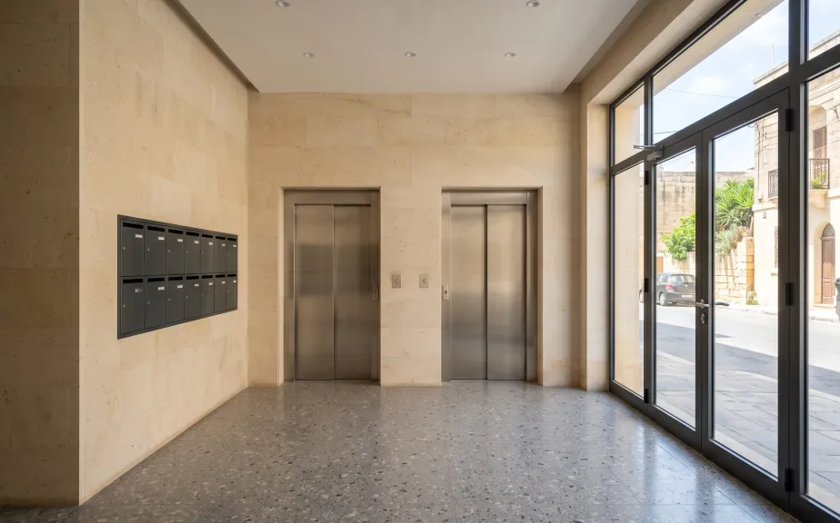 Lobby with twin stainless steel lift doors in a Gozo apartment block